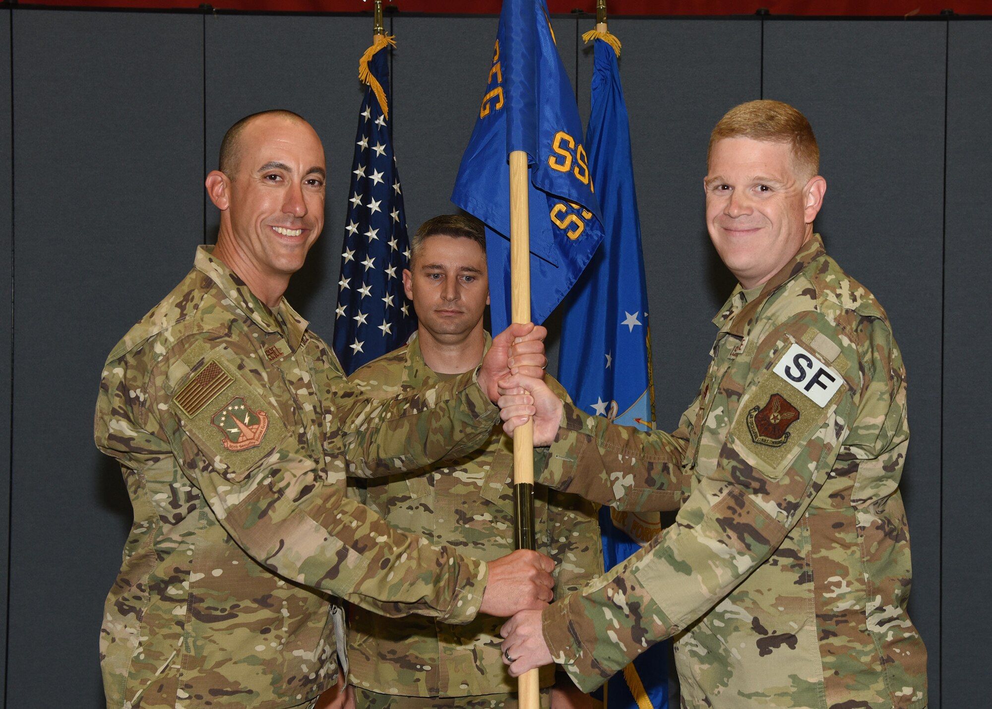 Colonel Damian Schlussel, 90th Security Forces commander, passes the guidon to Maj. Tim Marriner, 90th Security Support Squadron commander, during the 90th SSPTS change of command ceremony October 3, 2019 in the Peacekeeper Security Forces high bay on F.E. Warren Air Force Base, Wyo. The ceremony signified the transition of command from Maj. George Hern to Marriner. (U.S. Air Force photo by Glenn S. Robertson)