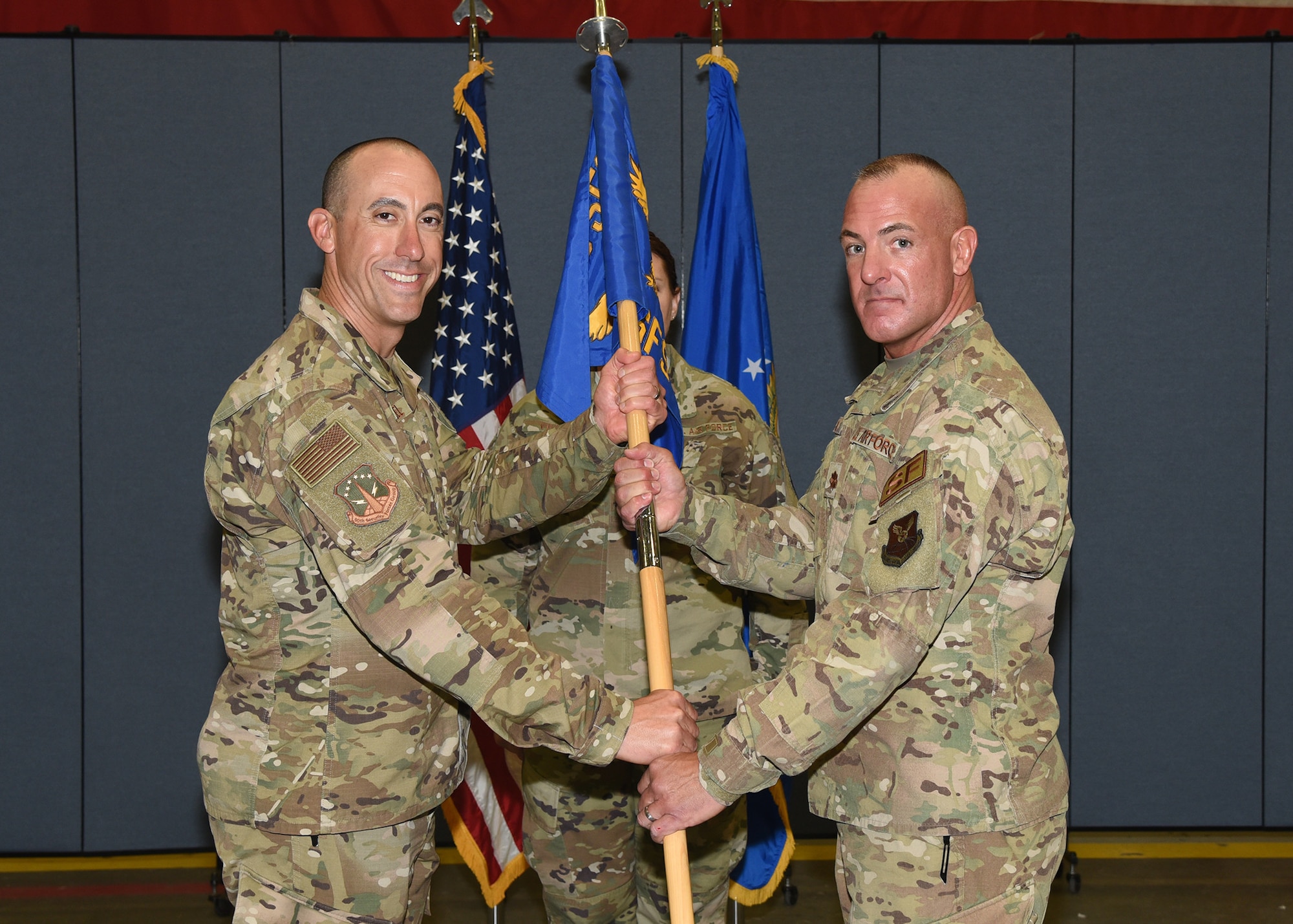 Colonel Damian Schlussel, 90th Security Forces commander, passes the guidon to Maj. George Hern, 90th Security Forces Squadron commander, during the 90th SFS assumption of command ceremony October 3, 2019 in the Peacekeeper Security Forces high bay on F.E. Warren Air Force Base, Wyo. The passing of the guidon symbolizes the authority and responsibility Hern now has as the commander of 90th SFS.  (U.S. Air Force photo by Glenn S. Robertson)