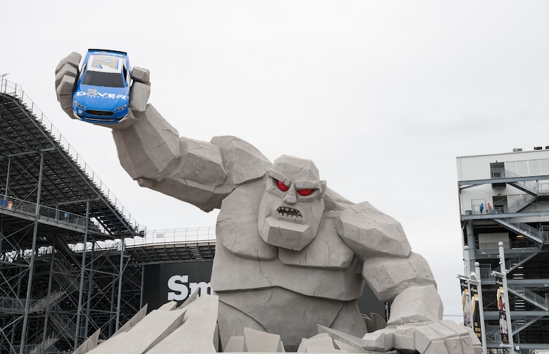 Miles the Monster holds a race car above race fans in Victory Plaza Oct. 6, 2019, at Dover International Speedway, Dover, Del. This race weekend is DIS’s 50th Anniversary celebration and the 100th NASCAR Cup Series race in the track’s history. (U.S. Air Force photo by Roland Balik)