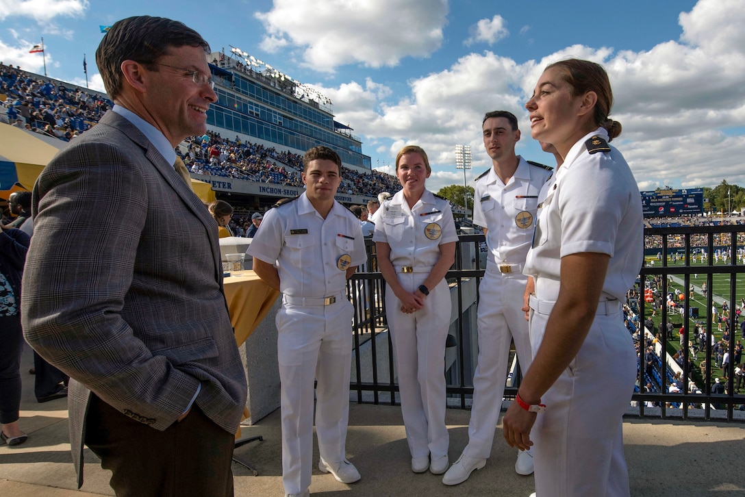 Defense Secretary Dr. Mark T. Esper talks with a group of midshipmen in a stadium.