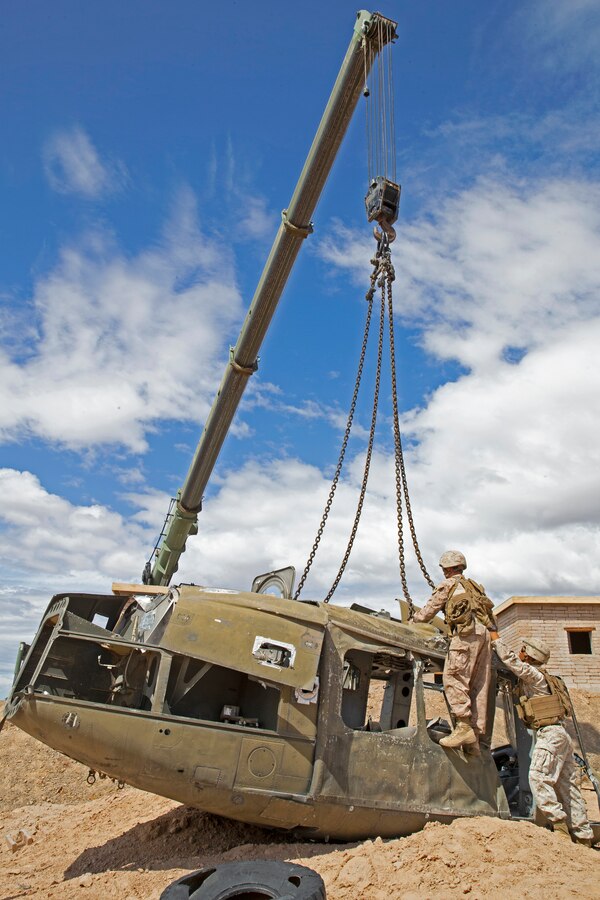 U.S. Marines with Marine Wing Support Squadron (MWSS) 372, Marine Wing Support Group 37, 3rd Marine Aircraft Wing, pull ratchet straps attached to a wrecked aircraft in support of an aircraft salvage and recovery exercise during Weapons and Tactics Instructor (WTI) course 1-20 at Site 2 in Yuma Proving Ground, Arizona, Sept. 25, 2019. WTI is a seven-week training event hosted by Marine Aviation Weapons and Tactics Squadron One (MAWTS-1), which emphasizes operational integration of the six functions of Marine Corps aviation in support of a Marine Air Ground Task Force. MAWTS-1 also provides standardized advanced tactical training and certification of unit instructor qualifications to support Marine aviation training and readiness, and assists in developing and employing aviation weapons and tactics. (U.S. Marine Corps photo by Cpl. Ursula V. Smith)