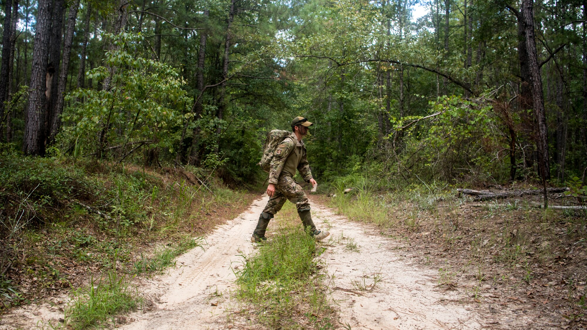 A Survival, Evasion, Resistance and Escape Specialist assigned to the 437th Operations Support Squadron walks across a dirt road during a survival, evasion, resistance, and escape exercise August 21, 2019 in North, South Carolina. SERE specialists assigned to the 437th Operations Support Squadron conducted this exercise in order to identify potential areas of improvement in both SERE training and equipment provided to aircrew in case of a potential isolating event. (U.S. Air Force photo/Airman 1st Class Duncan C. Bevan)