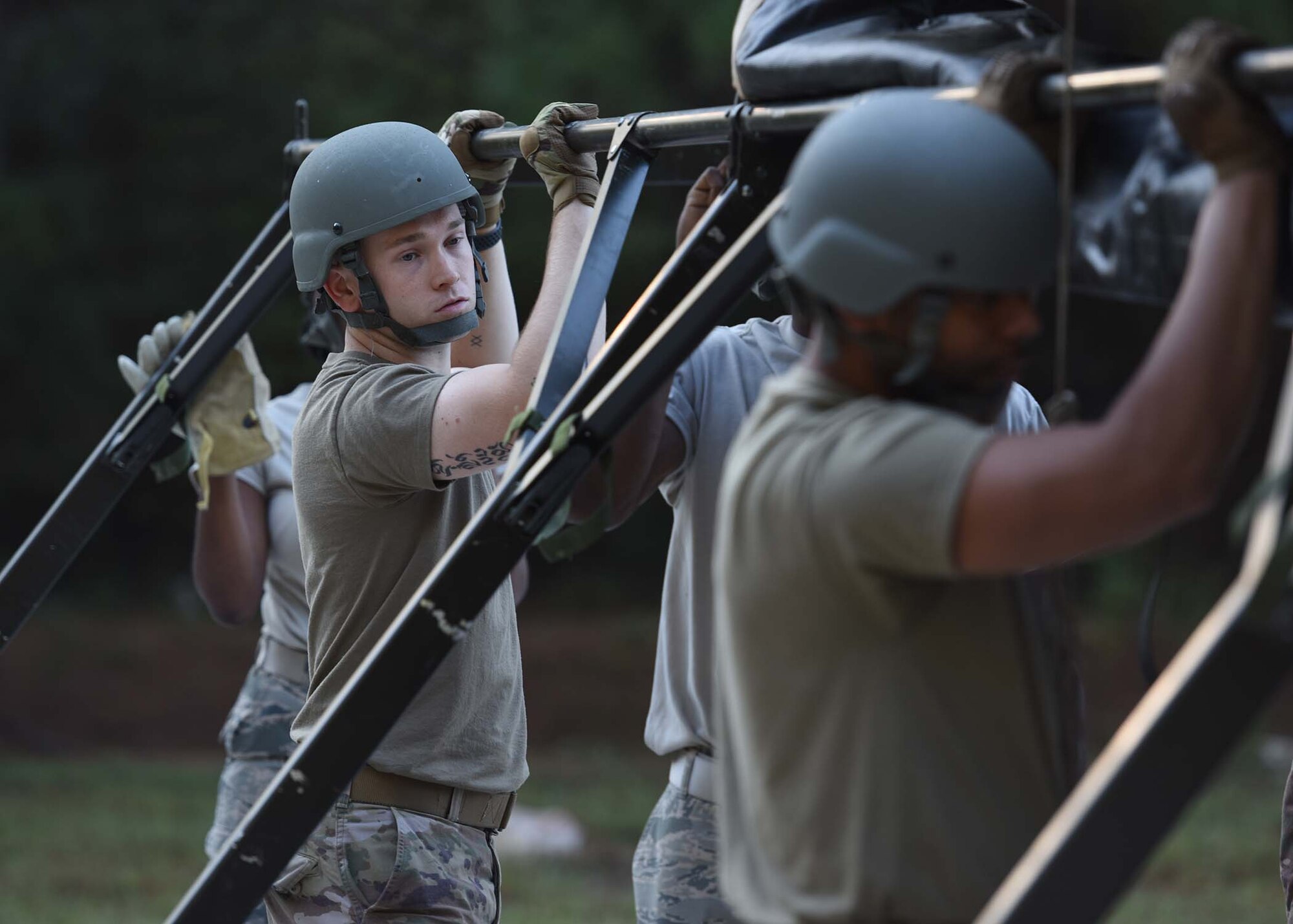 Airmen lift up a metal piece of a tent.