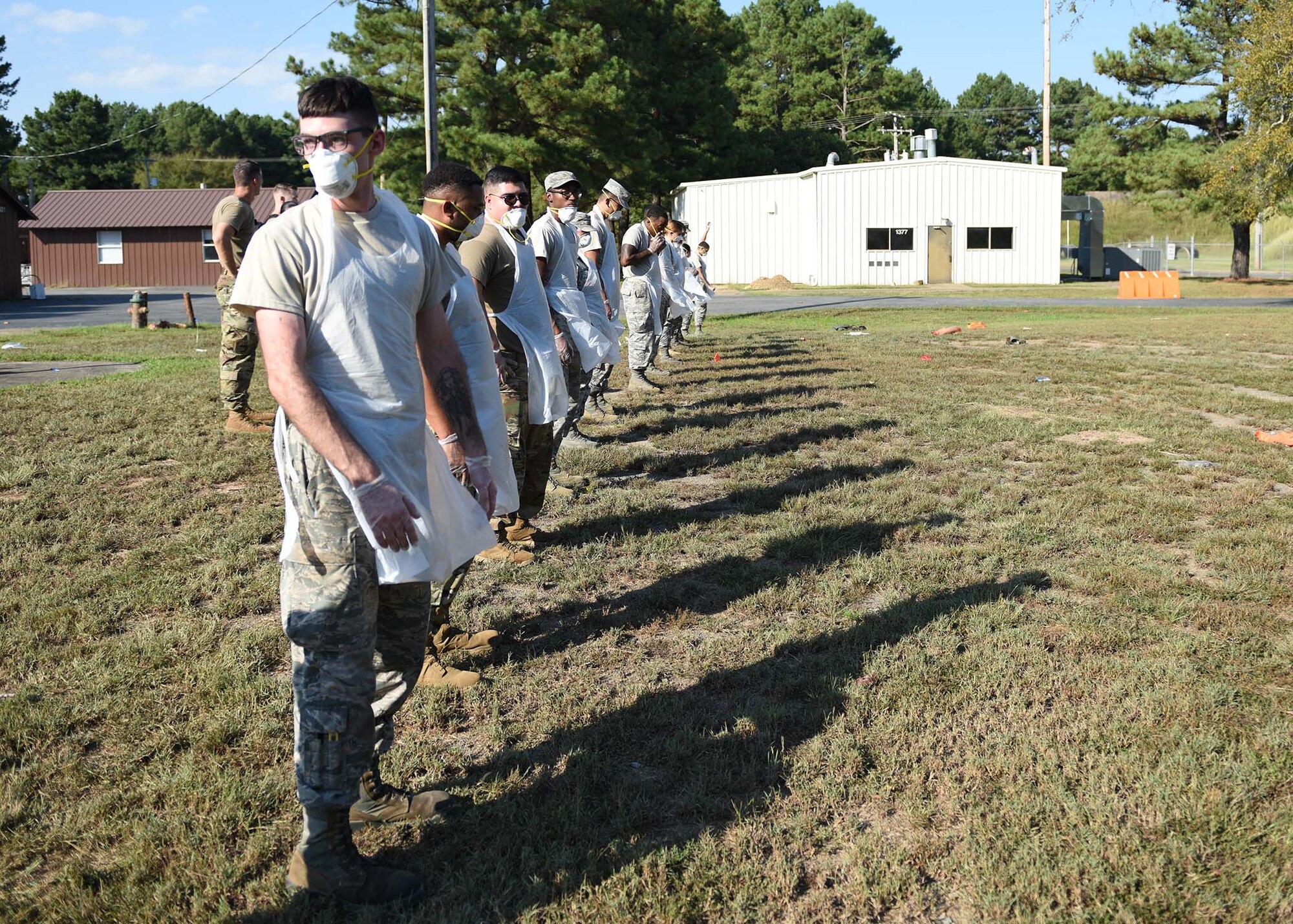 Airmen stand in a row in a field.
