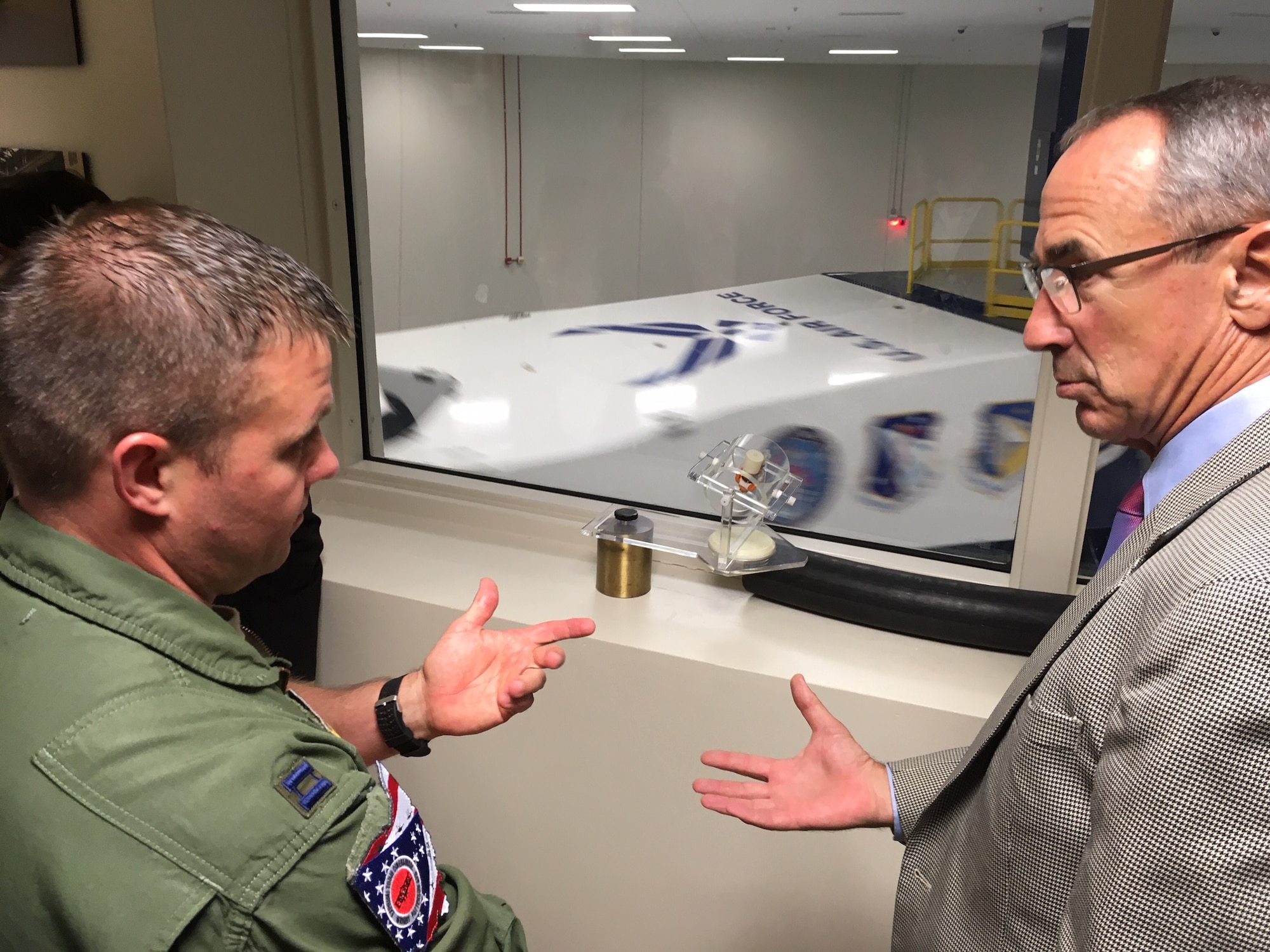 Capt. Adam Lohn, flight commander, Acceleration Branch, at the United States Air Force School of Aerospace Medicine, 711th Human Performance Wing’s Centrifuge training and research facility discusses current training program requirements with National Commission on Military Aviation Safety commissioner Gen. Raymond E. Johns, (USAF, Ret.) Sept. 11 during the commission’s visit to Wright-Patterson Air Force Base. The facility is the only human-rated centrifuge owned by the Department of Defense and provides training to approximately 1,200 students a year. (National Commission on Military Aviation Safety photo/Bryan Whitman)