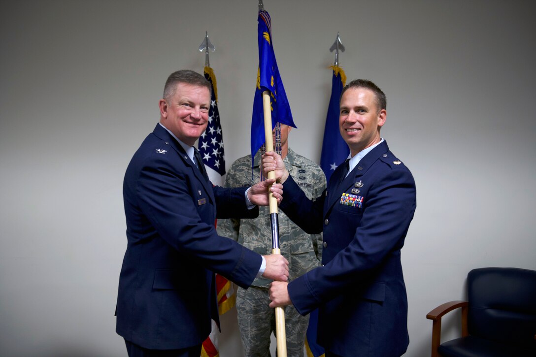 Col. Kent Hanson, 419th Mission Support Group commander, passes the squadron flag to Maj. Brian Weese, the new commander of the 419th Force Support Squadron, during a change of command ceremony