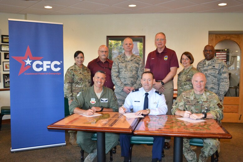 An image of Tinker Senior leaders signing pledge cards for Combined Federal Campaign.