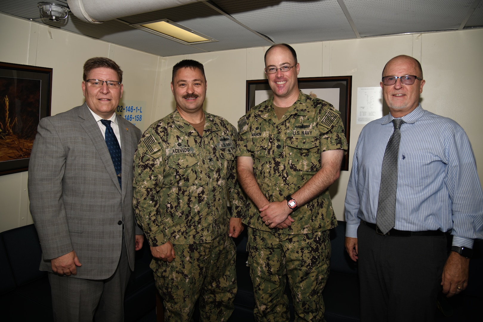 NSWC PHD Commanding Officer Capt. Ray Acevedo, Technical Director Paul Mann, and Deputy Technical Director Vance Brahosky pose for a photo with USS Ralph Johnson (DDG 114) Commanding Officer Cmdr. Casey Mahon during a meet and greet aboard the ship, Aug. 26.