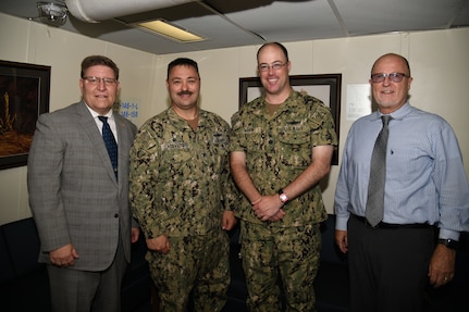 NSWC PHD Commanding Officer Capt. Ray Acevedo, Technical Director Paul Mann, and Deputy Technical Director Vance Brahosky pose for a photo with USS Ralph Johnson (DDG 114) Commanding Officer Cmdr. Casey Mahon during a meet and greet aboard the ship, Aug. 26.