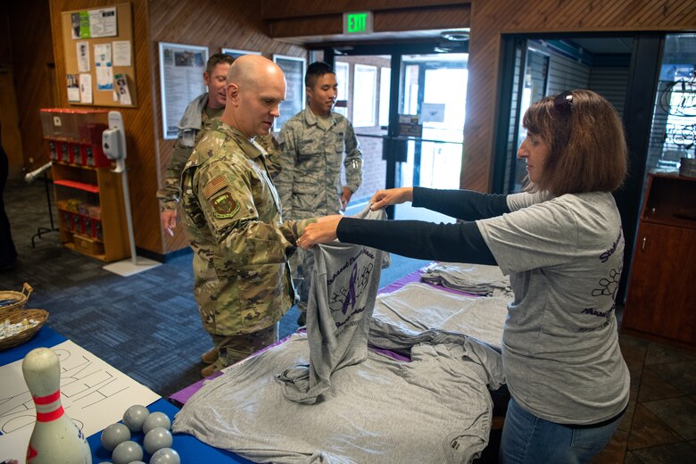 Master Sgt. Benjamin Davis, 50th Wing Staff Agency/ 50th Mission Support Group first sergeant, receives a free T-shirt during the Peterson Air Force Base Family Advocacy Program's second-annual Strike-Out Domestic Violence bowling tournament at the Bowling Center on Peterson AFB, Colorado, Oct. 1, 2019. The tournament was organized in support of National Domestic Violence Awareness Month, observed during the month of October. (U.S Air Force photo by Katie Calvert)