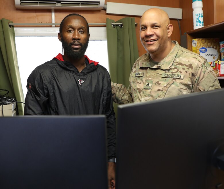 Logistics Management Specialist Jimmy Mapp (left) inspects his desk and office with his new boss, U.S. Army Corps of Engineers Afghanistan District Information Technology Chief Chris Brooks. , for example. Mapp has worked for USACE for six years. He started his Afghanistan deployment as a 90-day assignment and is now on his 10th month in country.