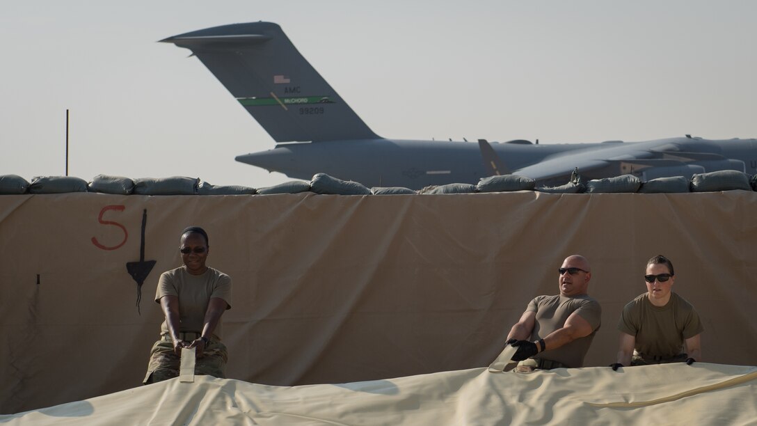 Chief Master Sgt. Sebrena Flagg-Briggs, 386th Expeditionary Logistics Readiness Squadron chief enlisted manager; Chief Master Sgt. Jason Colon, 386th Air Expeditionary Wing command chief and Lt. Col. Melissa Thurman, 386th ELRS commander, assist U.S. Air Force Airmen with the 386th ELRS fuels management flight, to position a fuel bladder at Ali Al Salem Air Base, Kuwait, Oct. 7, 2019. Fuel bladders are replaced every three-to-four years after they become unserviceable. (U.S. Air Force photo by Tech. Sgt. Daniel Martinez)