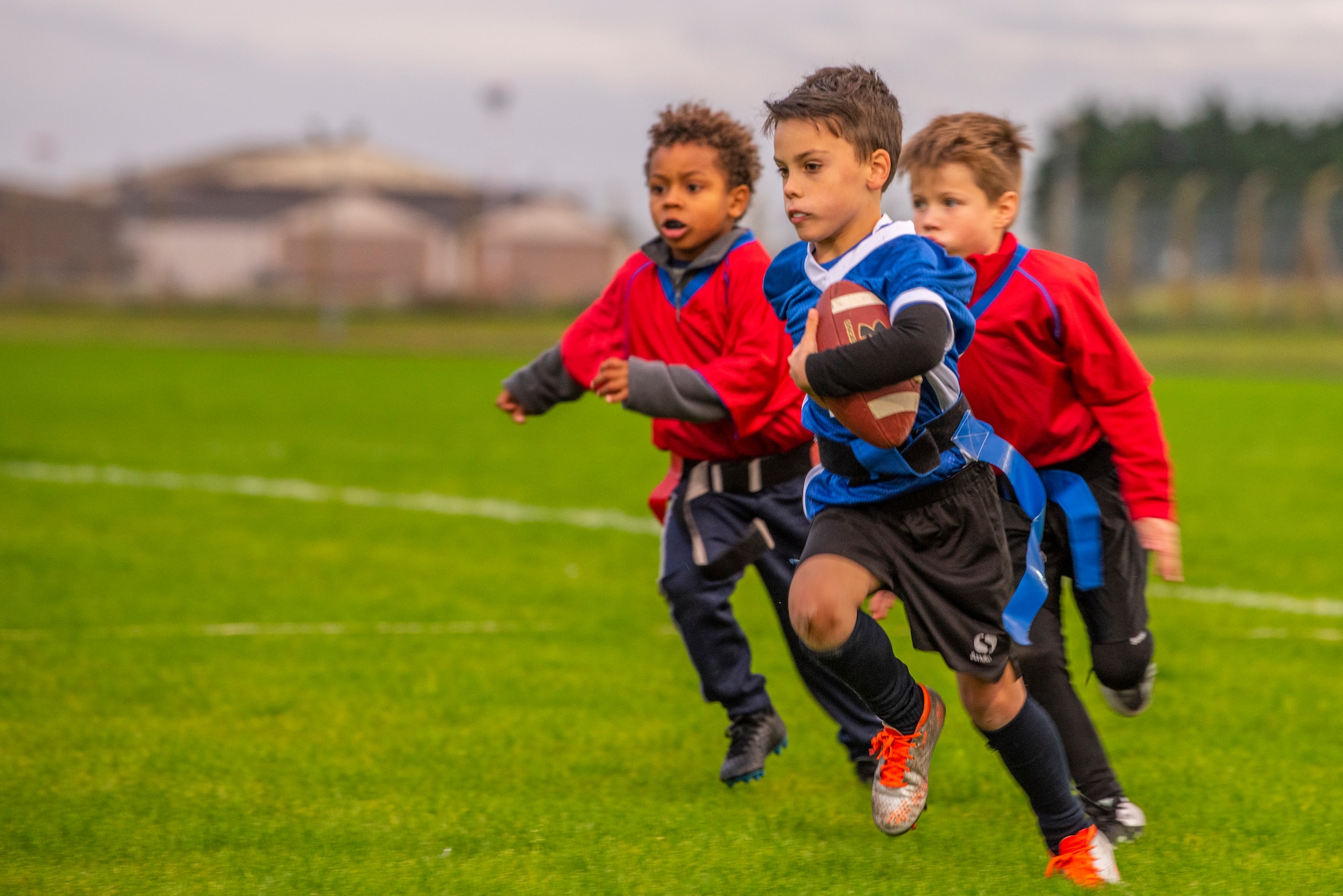 A flag football player runs past his opponents at Heritage Park Oct. 7, 2019, at RAF Mildenhall, England. The park reopened following a six-month renovation. (U.S. Air Force photo by Airman 1st Class Joseph Barron)