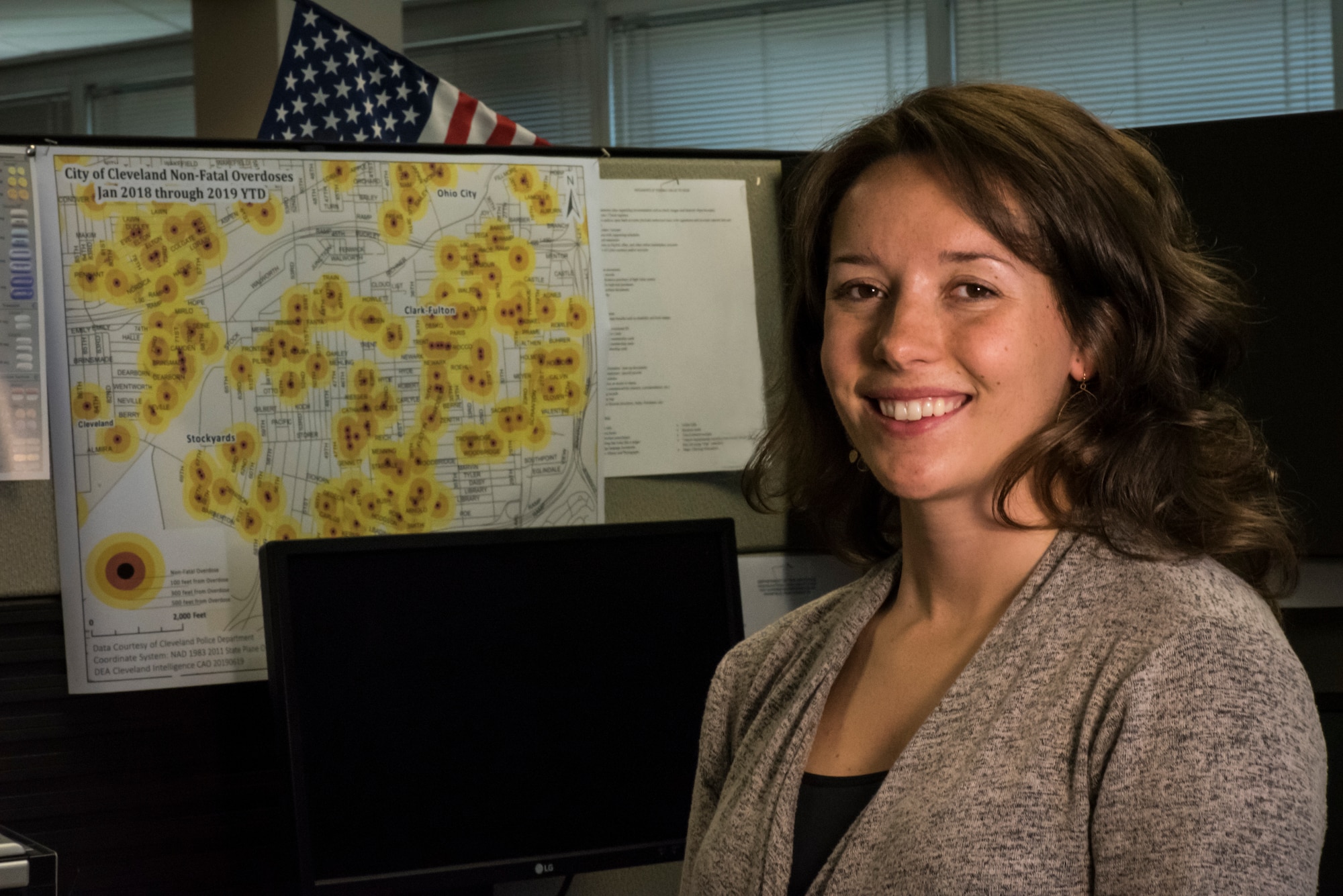 U.S. Air Force Staff Sgt. Carolyn Kinzel, a C-130H Hercules loadmaster assigned to the 179th Airlift Wing, Ohio Air National Guard, and an Ohio Air National Guard Counterdrug Task Force criminal analyst, poses in front of an overdose map she created Aug. 1, 2019, at the Drug Enforcement Administration (DEA), Cleveland, Ohio. The Ohio National Guard Counterdrug Task Force personnel provide support to law enforcement agencies and community based organizations in order to enhance efforts to counter and defeat the threat of illegal substances, trafficking and violence in Ohio. (U.S. Air National Guard photo by Airman 1st Class Alexis Wade)