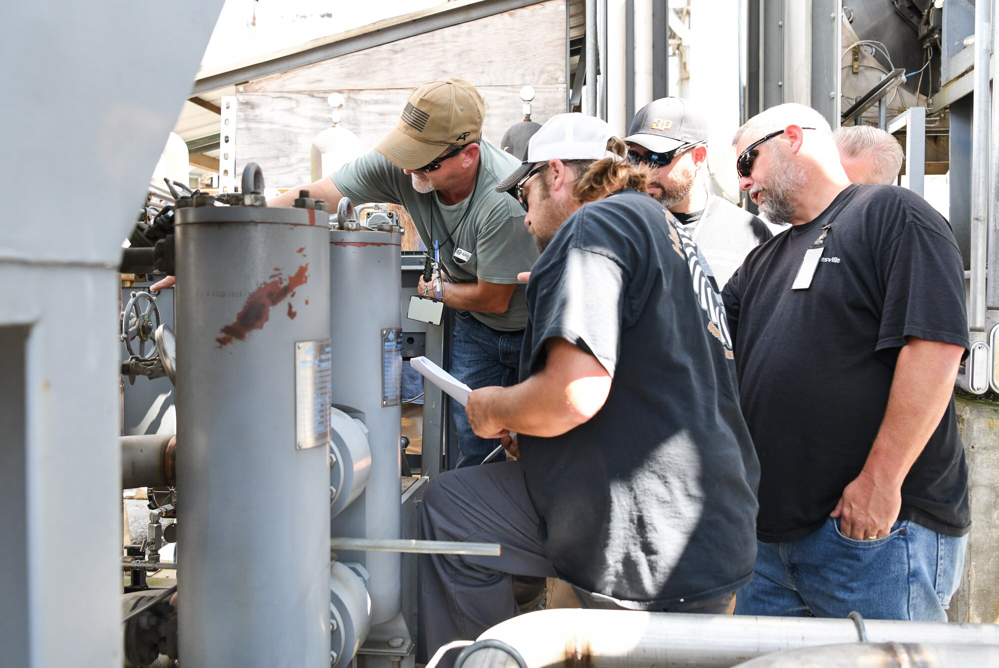 AEDC team members, from left, Kenny Seale, Robby Carr, Josh Keith, Matt Meacham and others look at an Engine Test Facility turbine lube oil during a walkthrough of a work instruction Sept. 3, during lead operations engineer training at Arnold Air Force Base. (U.S. Air Force photo by Jill Pickett) (This image was altered by obscuring badges for security purposes)