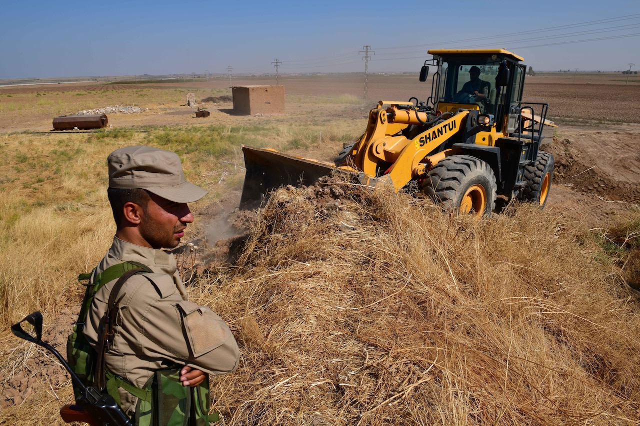 Soldier watches bulldozer.