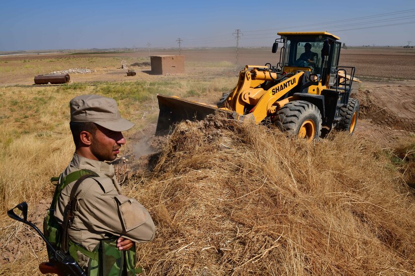 Soldier watches bulldozer.