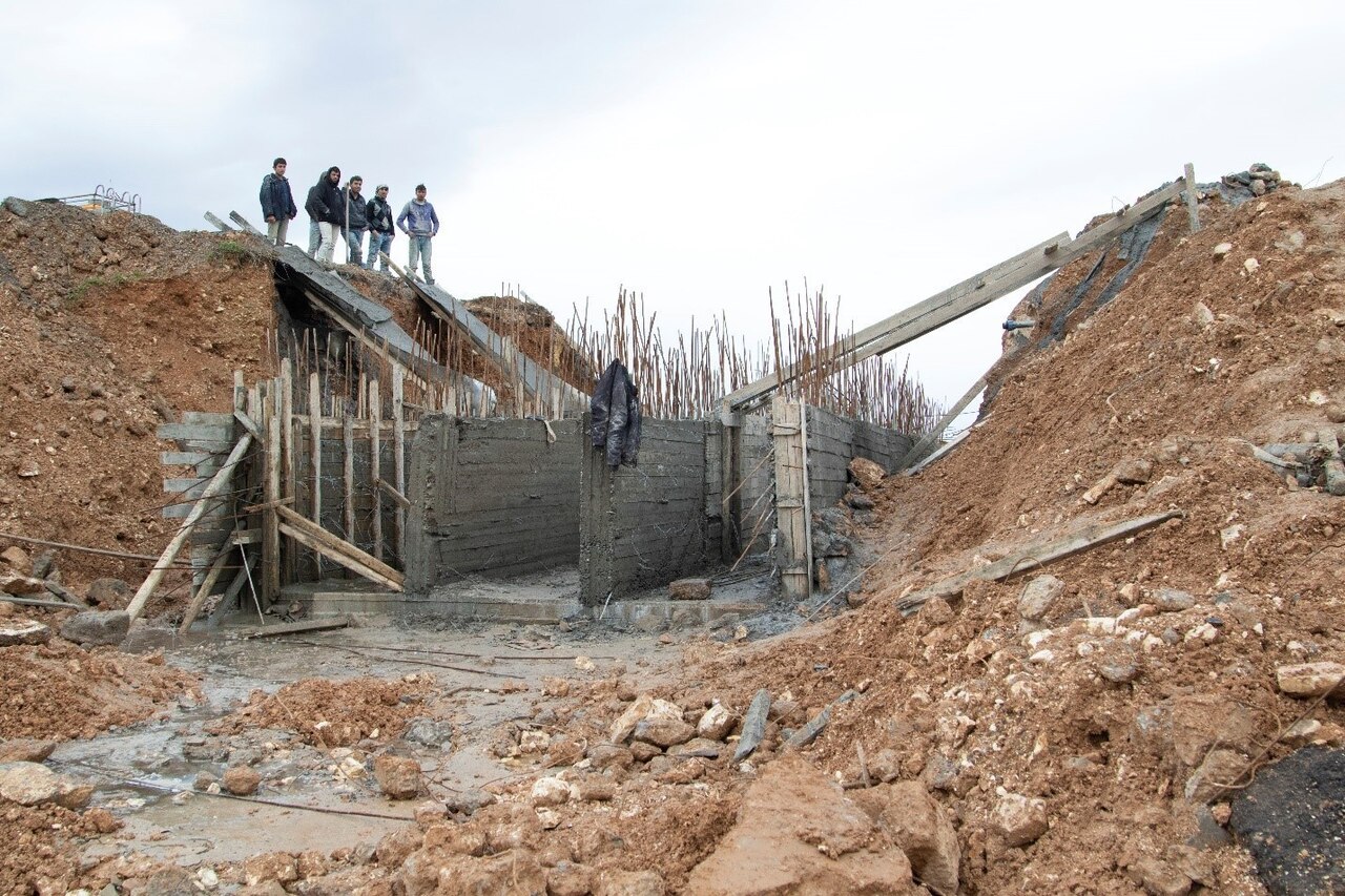 Syrian civilians look at remnants of bridge.