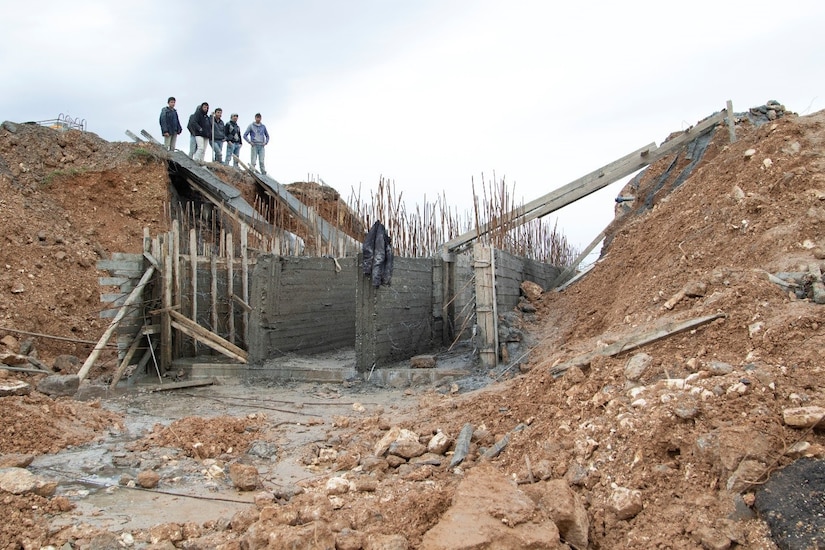Syrian civilians look at remnants of bridge.