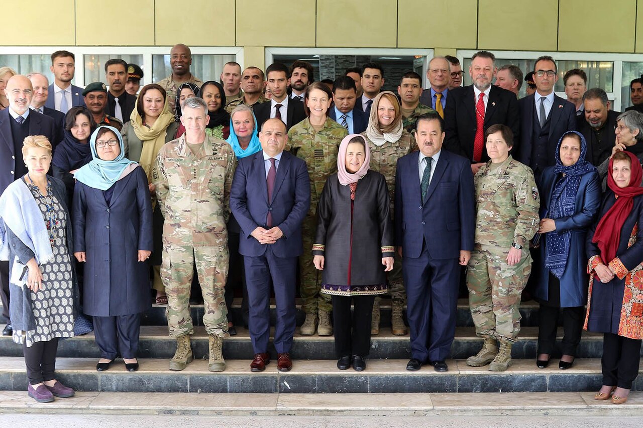 A group of civilians and military service members pose for photo.