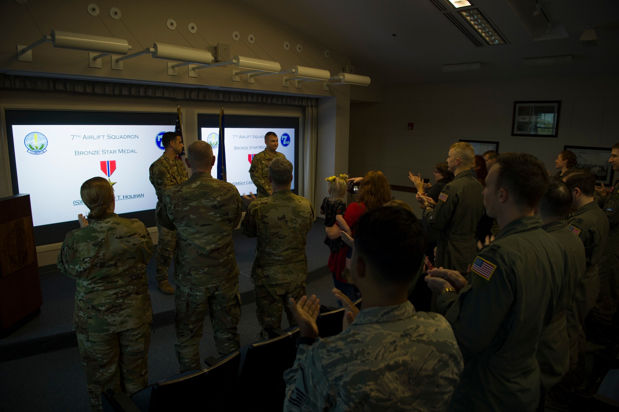 Friends, family and coworkers clap as Lt. Col. Jamil Musa, front left, 7th Airlift Squadron commander, presents Master Sgt. Casey Holihan, 7th AS superintendent, with a Bronze Star Medal during a ceremony at Joint Base Lewis-McChord, Wash., Oct. 7, 2019. Holihan received the medal for his actions while deployed to Forward Operating Base Oqab, Kabul, Afghanistan.