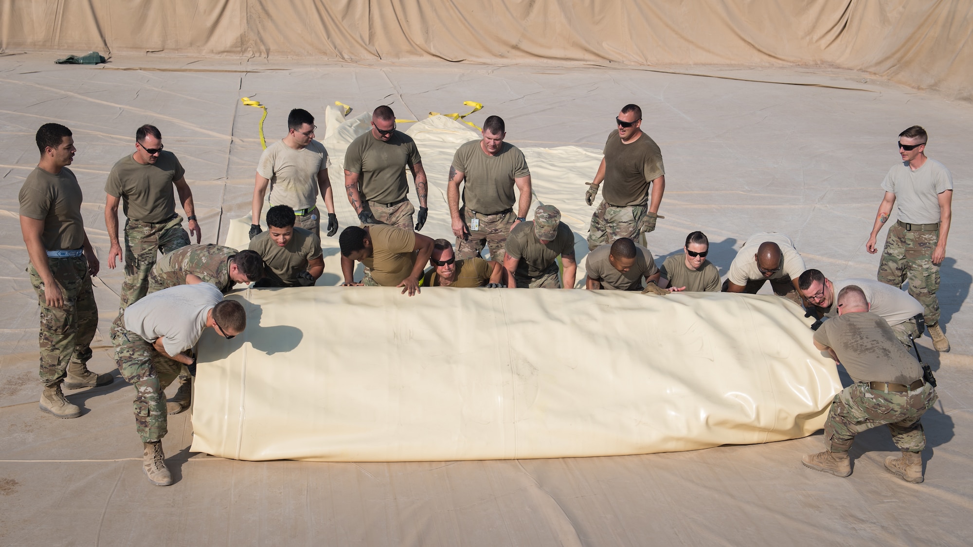 U.S. Air Force Airmen, from the 386th Expeditionary Logistics Readiness Squadron fuels management flight, work together to unroll a new empty fuel bladder at Ali Al Salem Air Base, Kuwait, Oct. 7, 2019. Fuel bladders are replaced every three-to-four years after they become unserviceable. (U.S. Air Force photo by Tech. Sgt. Daniel Martinez)