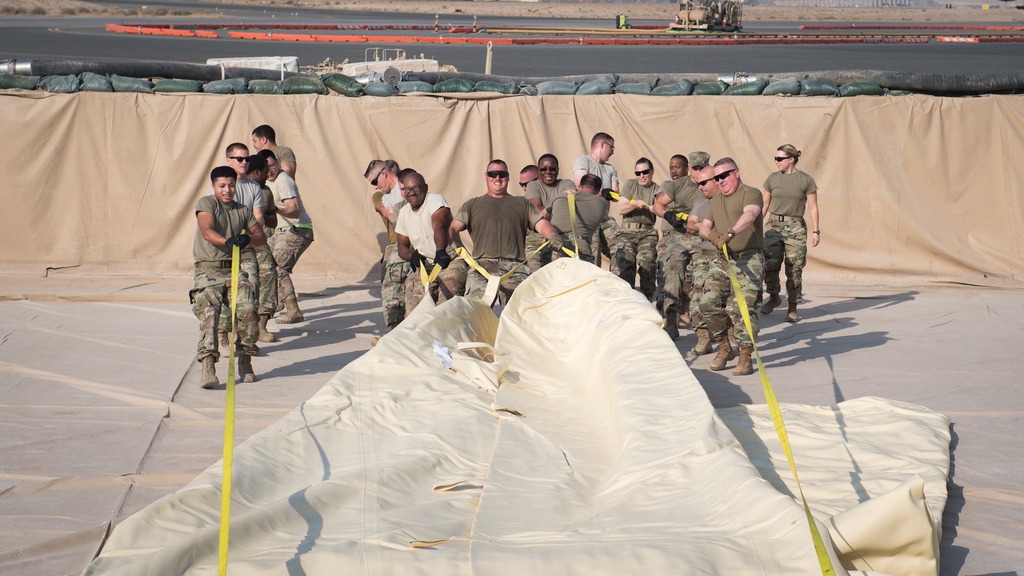 U.S. Air Force Airmen, from the 386th Expeditionary Logistics Readiness Squadron fuels management flight, Col. Rod Simpson, 386th Air Expeditionary Wing commander (second from right) and Chief Master Sgt. Jason Colon, 386th AEW command chief (third from right), drag an empty fuel bladder into position at Ali Al Salem Air Base, Kuwait, Oct. 7, 2019. An empty fuel bladder can weigh as much as 4,600 pounds. (U.S. Air Force photo by Tech. Sgt. Daniel Martinez)