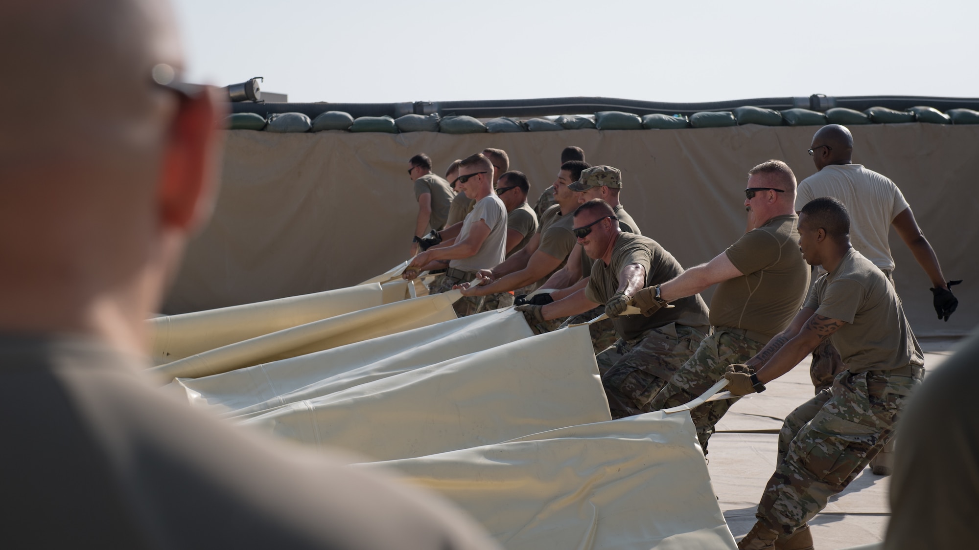 U.S. Air Force Airmen, from the 386th Expeditionary Logistics Readiness Squadron fuels management flight, and Col. Rod Simpson (second from right), 386th Air Expeditionary Wing commander, work together to drag a newly-unrolled fuel bladder into position at Ali Al Salem Air Base, Kuwait, Oct. 7, 2019. An empty fuel bladder can weigh as much as 4,600 pounds. (U.S. Air Force photo by Tech. Sgt. Daniel Martinez)