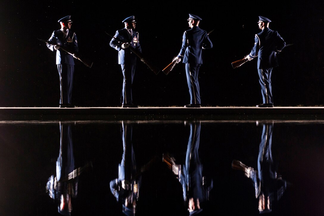 Four members of U.S. Air Force Honor Guard practice at night.