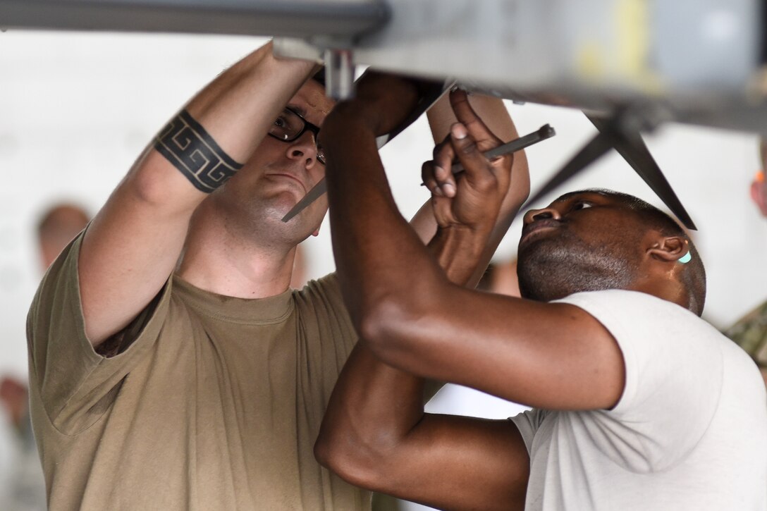 U.S. Air Force Staff Sgt. Demetrious Moutos, left, Senior Airman Josef Thompson, 77th Aircraft Maintenance Unit (AMU) load crew members work together to finish loading munitions on an F-16CM Viper during the quarterly load crew competition at Shaw Air Force Base, South Carolina, Oct. 7, 2019.