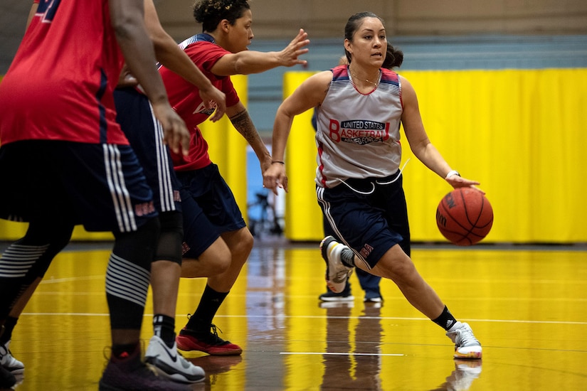 Woman dribbles a basketball as two opponents try to guard her.