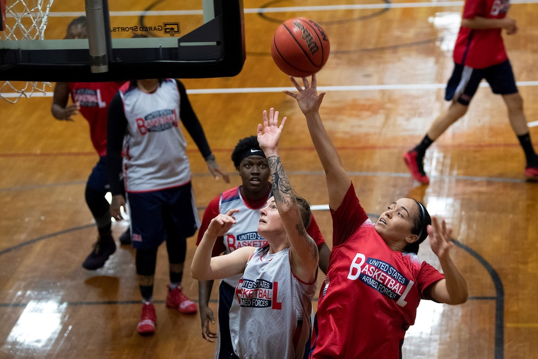Woman jumps to shoot near the basket as a defender tries to block the shot.