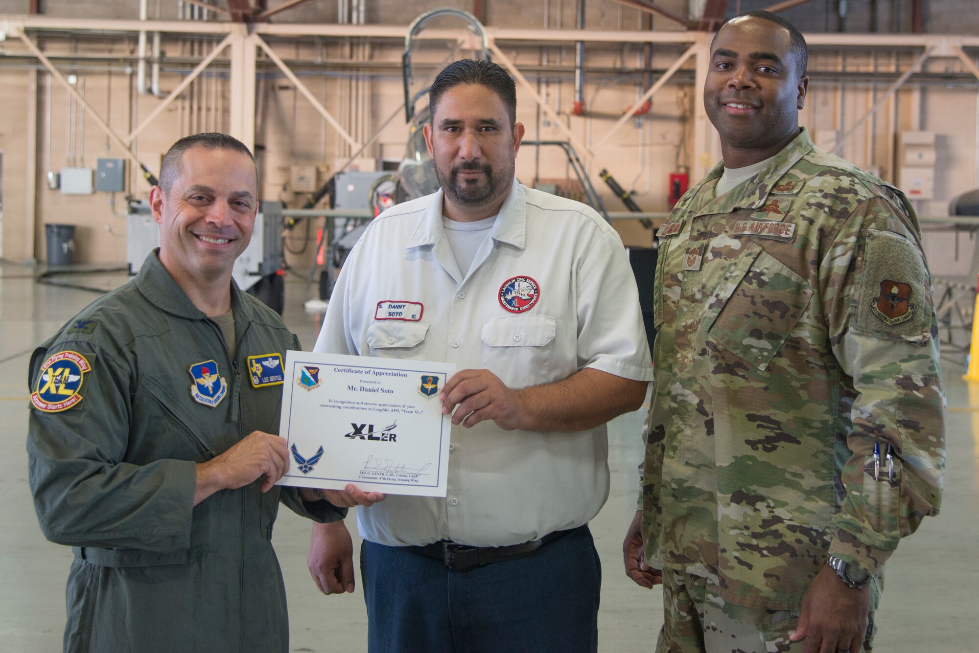 Daniel Soto, a 47th Maintenance Directorate aircraft maintenance supervisor, receives an award from Col. Lee Gentile, 47th Flying Training Wing commander, and Command Chief Master Sgt. Robert Zackery III, 47th FTW command chief at Laughlin Air Force Base, Texas, Oct. 3, 2019. Soto was chosen by wing leadership to be the “XLer of the Week” of Sept. 30, 2019. (U.S. Air Force photo by Senior Airman Daniel Hambor)