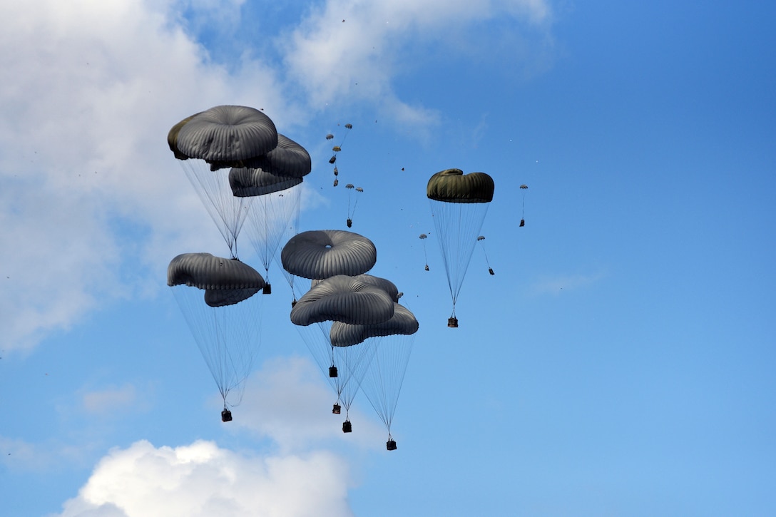 Parachutes carrying supplies descend in the sky.