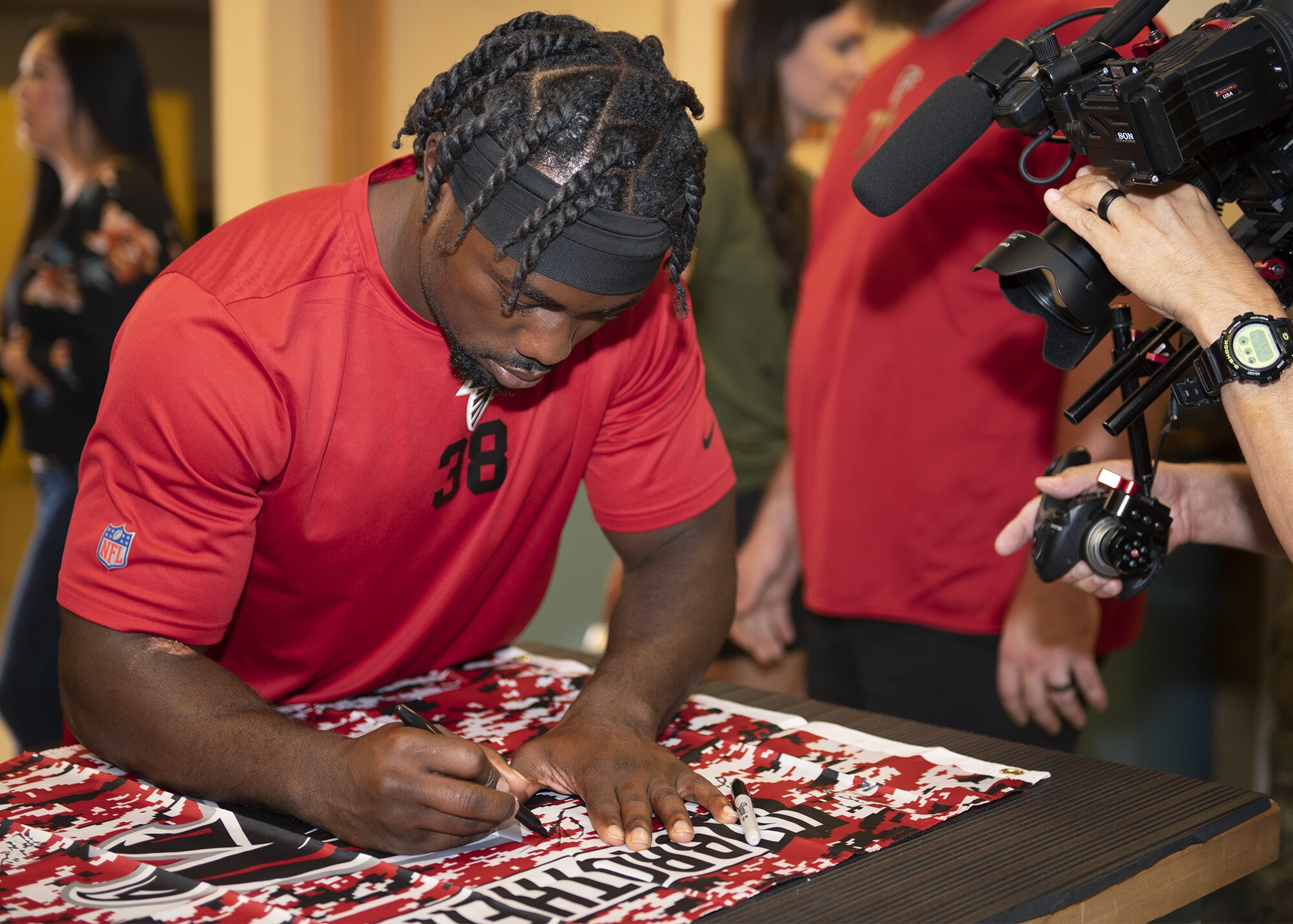 Kenjon Barner, Atlanta Falcons running back, signs memorabilia during a tour of the 56th Operations Support Squadron Aircrew Flight Equipment’s facility Oct. 8, 2019, at Luke Air Force Base, Ariz.