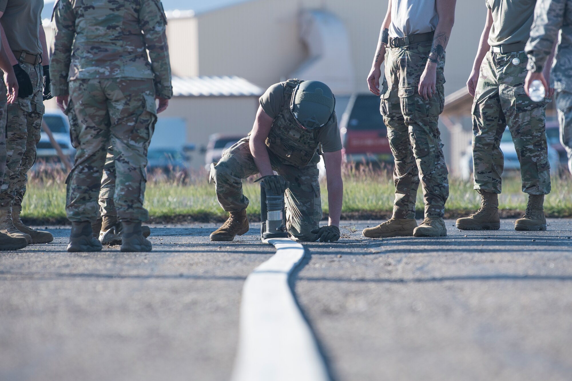 Airman 1st Class Caleb McDonald, 27th Special Operations Logistics Readiness Squadron fuels operator, rolls up a fuel hose as teammates watch during the Forward Air Refueling Point tryouts at Cannon Air Force Base, N.M., October 9, 2019. The hose is only folded after members squeegee out all remaining fuel so it can be carried to a sled. (U.S. Air Force photo by Senior Airman Vernon R. Walter III)