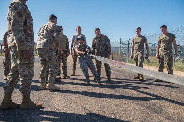 Airman Basic Sarah De La Rosa, 27th Special Operations Logistics Readiness Squadron fuels technician, drags a fuel hose as her team encourages her during the Forward Air Refueling Point tryouts at Cannon Air Force Base, N.M., October 9, 2019. The hose dragging is meant to simulate dragging a hose to an awaiting aircraft. (U.S. Air Force photo by Senior Airman Vernon R. Walter III)