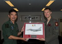Japan Air Self-Defense Force Maj. Gen. Masahito Monma, the Japan Air Self-Defense Force 6th Air Wing commander, and U.S. Air Force Capt. Phillip McCoy, a 13th Fighter Squadron F-16 Fighting Falcon pilot, poses for a photo with an F-16 framed photo during an aviation training relocation at Komatsu Air Base, Japan, Sept. 30, 2019. McCoy presented Monma this item as a gift to express his gratitude toward JASDF’s hospitability, support and friendship. (U.S. Air Force photo by Senior Airman Collette Brooks)