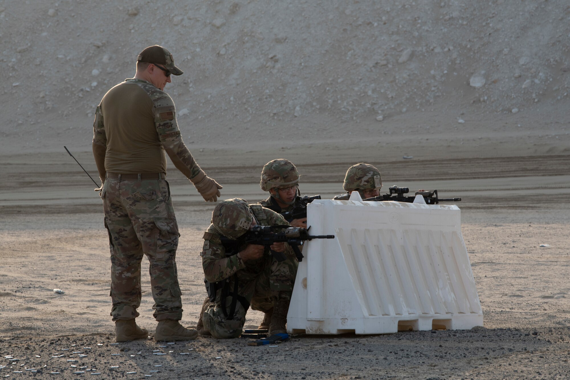 380th Expeditionary Security Forces Squadron Airmen take cover and fire from behind a barrier during a simunition proficiency firing  course held on Al Dhafra Air Base, United Arab Emirates, Sept. 29, 2019.