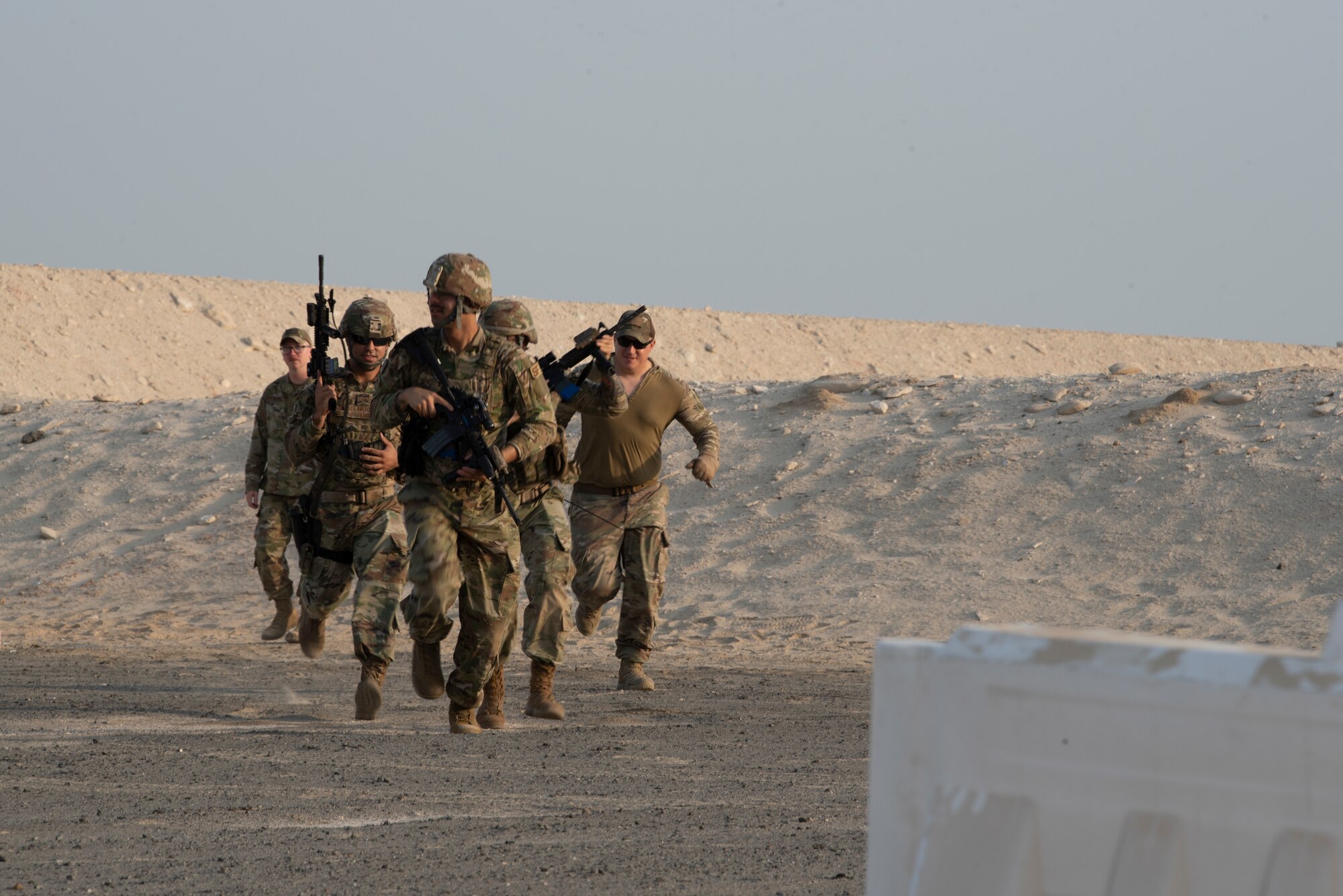 380th Expeditionary Security Forces Squadron Airmen run toward a barrier to take cover during a simunition proficiency firing course held on Al Dhafra Air Base, United Arab Emirates, Sept. 29, 2019.