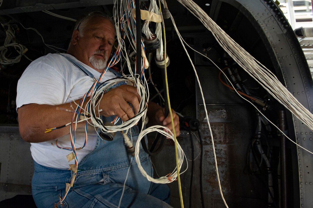 Jack Scott, electrician assigned to Corpus Christi Army Depot, Texas, repositions wires in an HH-60G Pave Hawk during a phase inspection Oct. 9, 2019, at Moody Air Force Base, Ga. Airmen assigned to the 23d Maintenance Group and contract maintainers disassemble, inspect and repair the HH-60 after every 600 flight hours. These maintainers continually work to ensure the aircraft are safe and reliable for search and rescue missions. (U.S. Air Force photo by Airman Azaria E. Foster)