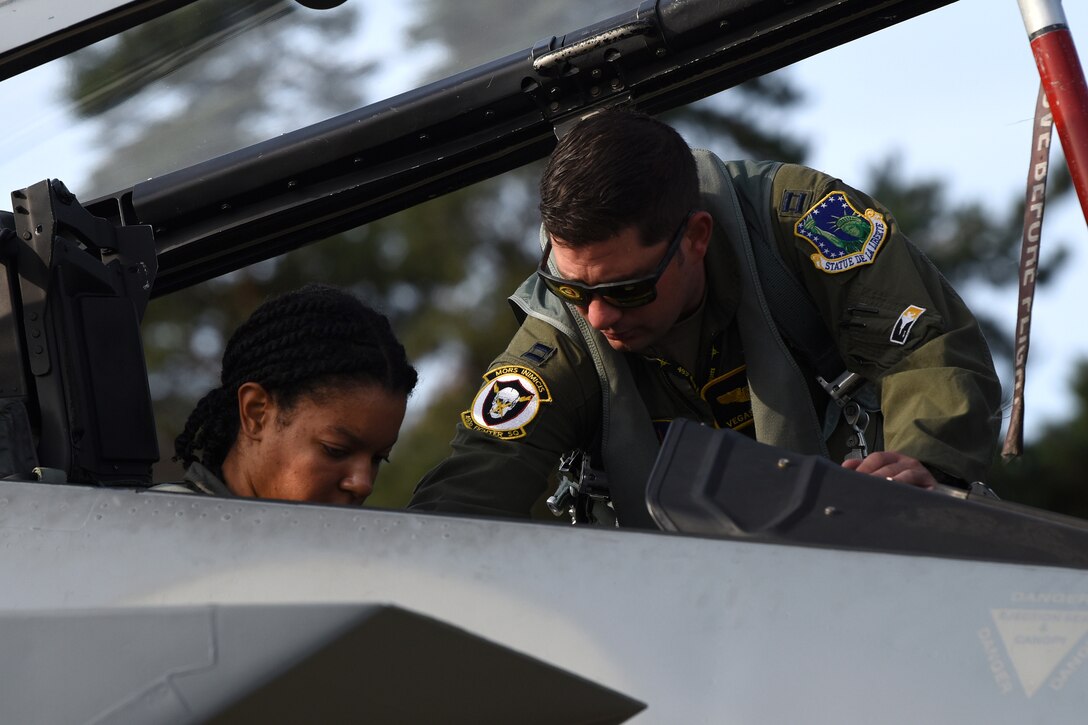 Captain Robert Volsey, 493rd Fighter Squadron pilot, helps strap in Senior Airman Danielle Jansen, 493rd FS intelligence analyst, during a familiarization flight at Royal Air Force Lakenheath, England, Aug. 21, 2019. Familiarization flights are authorized for individuals who normally have aviation-related responsibilities with aircraft and missions. (U.S. Air Force photo by Airman 1st Class Madeline Herzog)