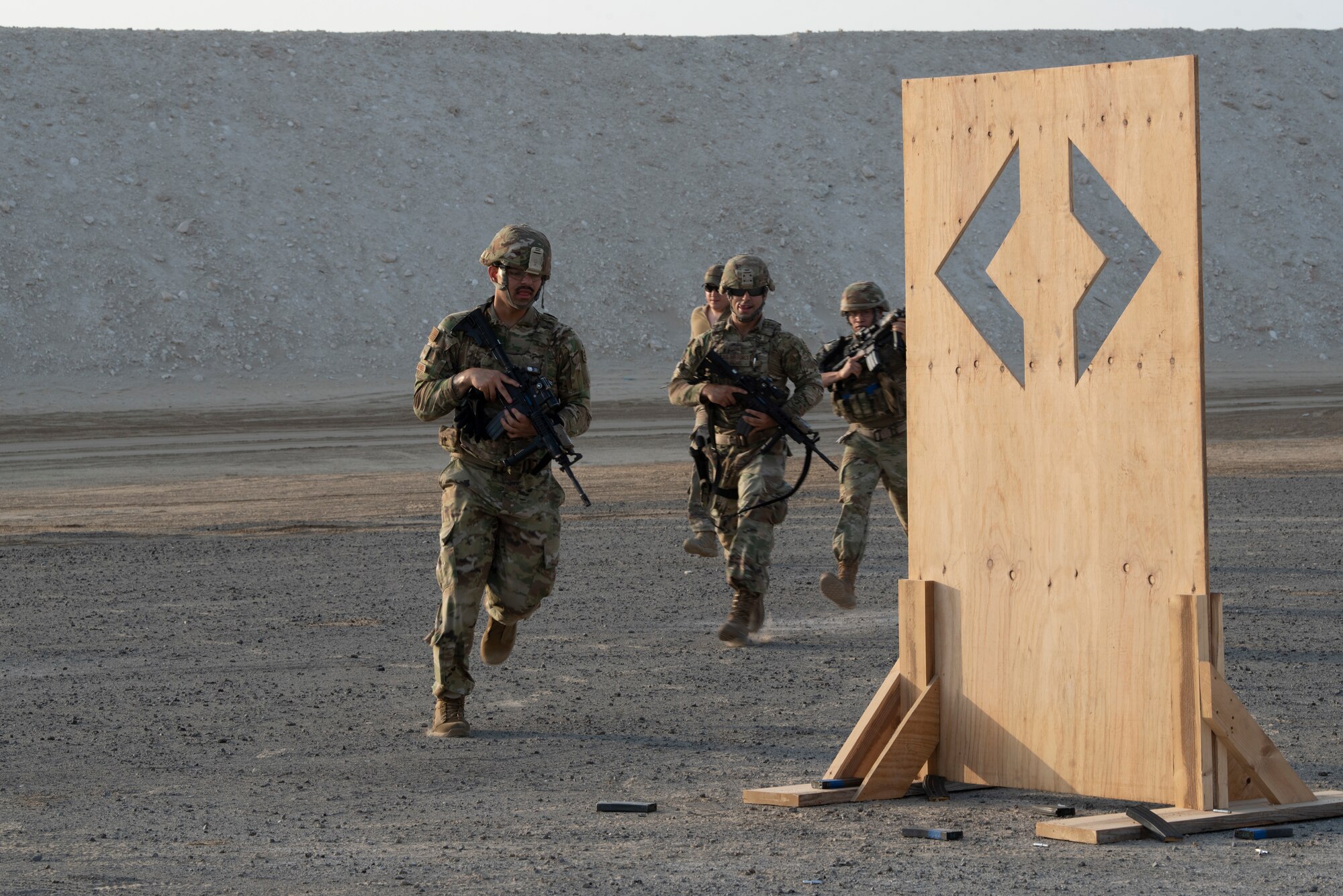 380th Expeditionary Security Forces Squadron Airmen run toward a barrier to take cover during a simunition  proficiency firing  course held on Al Dhafra Air Base, United Arab Emirates, Sept. 29, 2019.