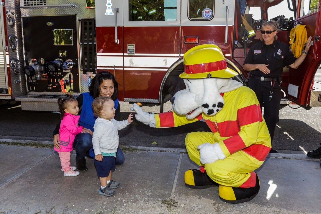 Children of the Child Development Center lined up to give Sparky, Fire Prevention mascot, a high-five during the Fire Department's visit to the CDC aboard Marine Corps Logistics Base Barstow, Calif., Oct. 9. (U.S. Marine Corps photo by Jack J. Adamyk)