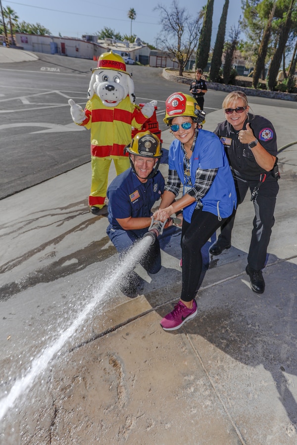 Julie Perez, Child Development Center assistant program leader, enjoys firing the fire hose at Fire Station 401 aboard Marine Corps Logistics Base Barstow, Calif., Oct. 8. The week of Oct. 6 through Oct. 12 is Fire Prevention Week both on and off base, where firefighters and fire prevention officers remind the community about fire safety and what to do in case of a fire.(U.S. Marine Corps photo by Jack J. Adamyk)