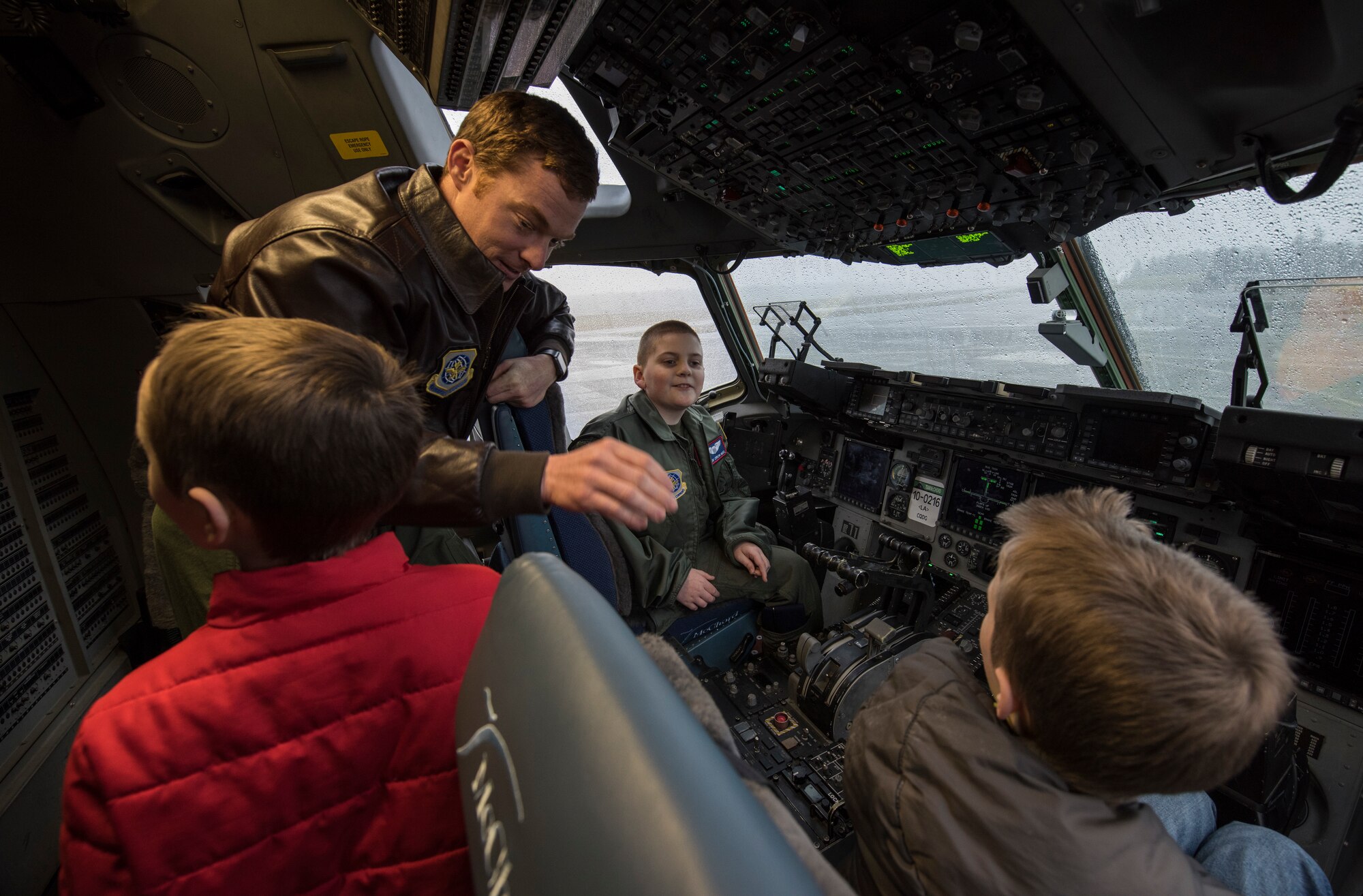 Capt. Hatton Updike, 4th Airlift Squadron pilot, tells McKay Neel (back right), McChord’s newest Pilot for a Day participant, and two friends about the features of a C-17 Globemaster III during a McChord Field tour at Joint Base Lewis-McChord, Wash., Feb. 20, 2018. McKay, along with his family and friends, spent the day learning about life at as an Airman and ended it with cake and ice cream at the 4th Airlift Squadron.