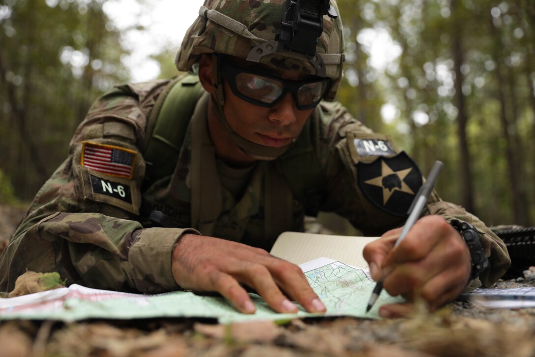 A soldier uses a pen to write on a map.