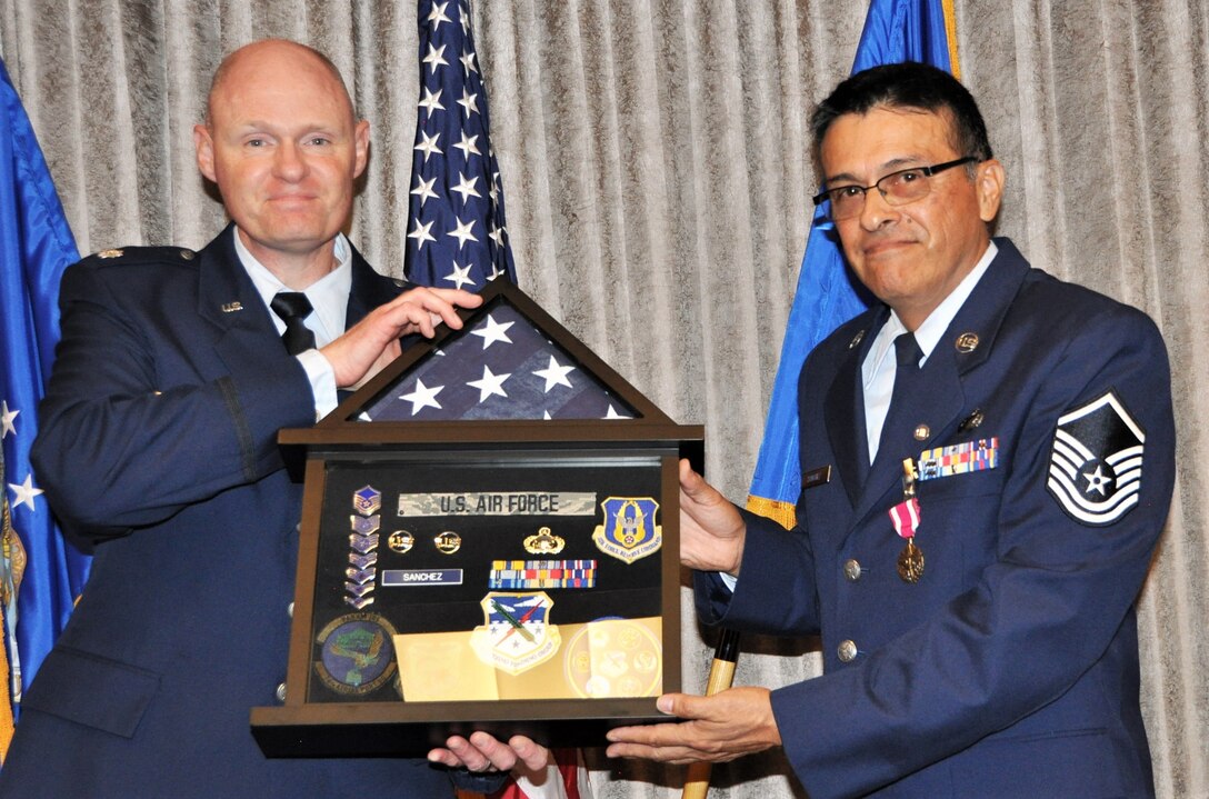 Master Sgt. Robert Sanchez, 340th Flying Training Group education and training chief, accepts a custom shadow box from 340th Flying Training Group Director of Personnel and Manpower Lt. Col. Mark Hiatt during Sanchez's Sept. 13 retirement ceremony at Joint Base San Antonio-Randolph, Texas. (U.S. Air Force photo by Janis El Shabazz)