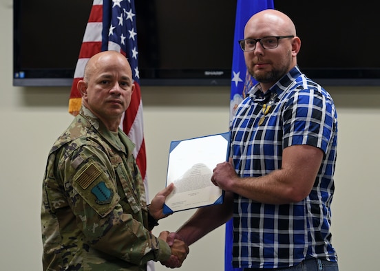 U.S. Air Force Col. Andres Nazario, 17th Training Wing commander, presents Special Agent, Kyle Carter, with The Air Force Commendation Medal on Goodfellow Air Force Base, Texas, Oct. 9, 2019, for his acts of courage in providing first aid to victims of a stabbing at a local nightclub Sept. 12, 2019. Carter provided immediate first aid to the victims and briefed paramedics of the incident before the victims were transported to a local hospital. (U.S. Air Force photo by Airman 1st Class Robyn Hunsinger/Released)