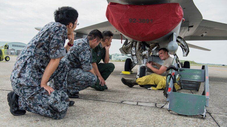 U.S. Air Force Senior Airman Ryan Pancheri, a 13th Aircraft Maintenance Unit dedicated crew chief, shows Maj. Gen. Masahito Monma, the Japan Air Self-Defense Force 6th Air Wing  commander, a nose wheel steering system on an F-16 Fighting Falcon during an aviation training relocation at Komatsu Air Base, Japan, Oct. 2, 2019. Airmen showed leadership of Komatsu AB the inner workings of the F-16 to increase bilateral relations, shared knowledge and friendship. (U.S. Air Force photo by Senior Airman Collette Brooks)